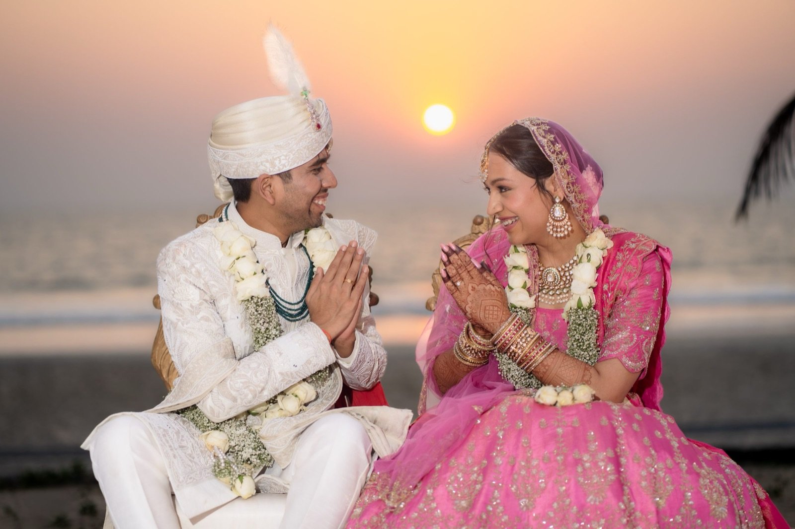 Achaman and Saumya with folded hands at sunset on the beach at their Goa wedding