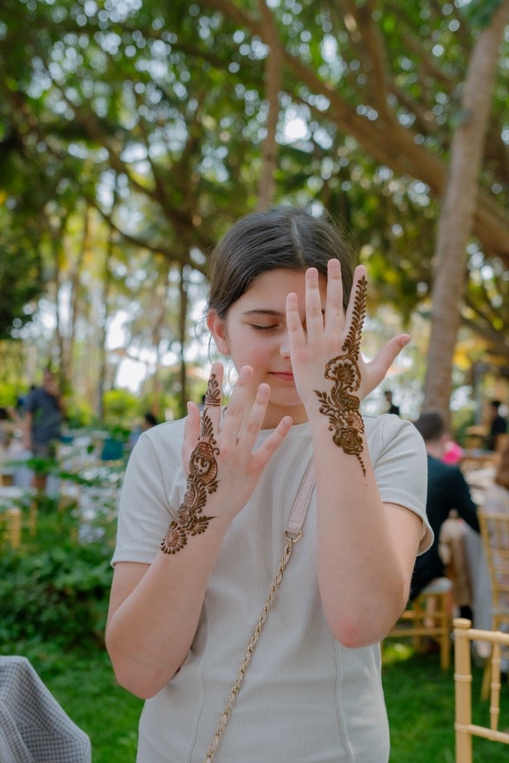 A guest laughing as she shows off her henna