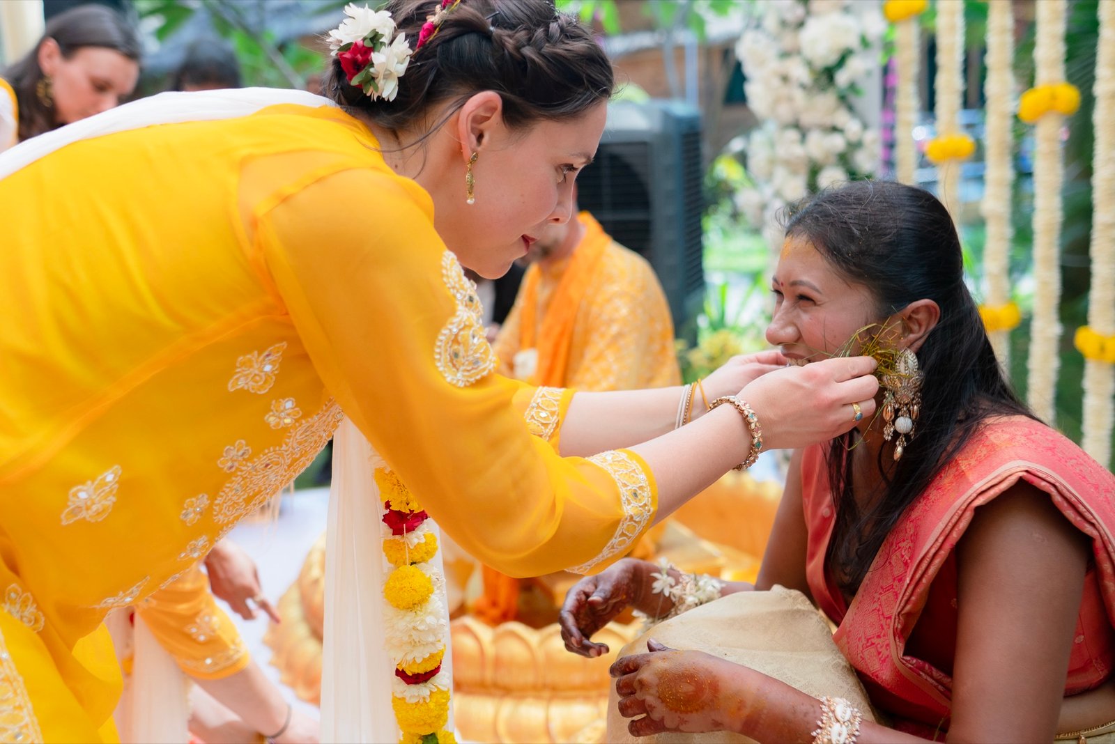 A guest smoothing haldi onto the bride's face at her haldi ceremony