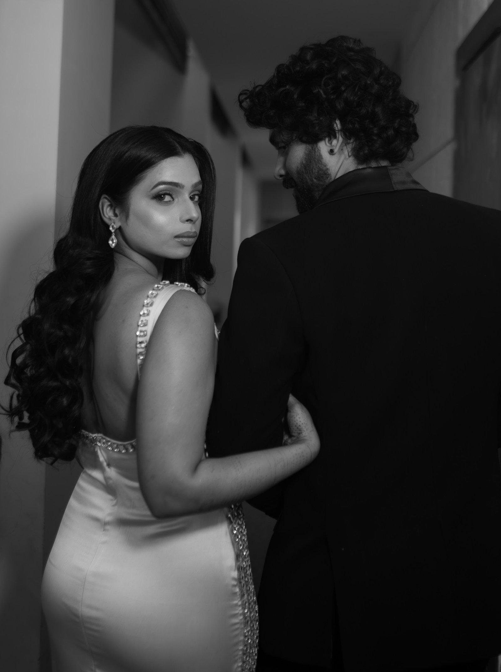 Black and white couple portrait in Mumbai, the woman looking back over her shoulder as she holds her partner's arm