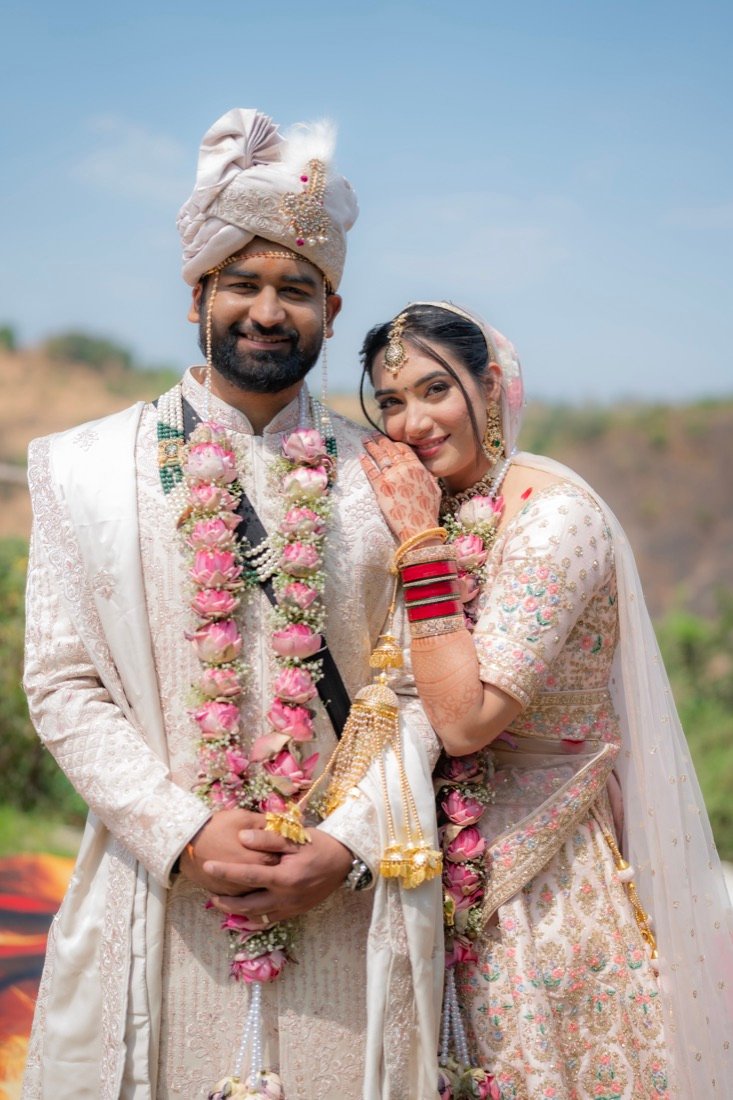 Shivani and Abhishek in rose garlands on a hillside on their wedding day